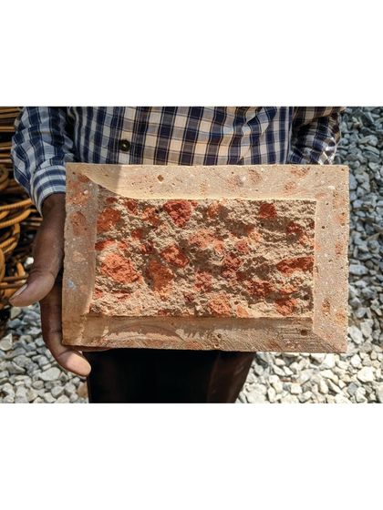 (Duplicate of 67) A close-up of the debris block used in our Bangalore house, held by a craftsman. The block's exterior is smooth, but its core reveals the recycled brick and concrete from the original site.