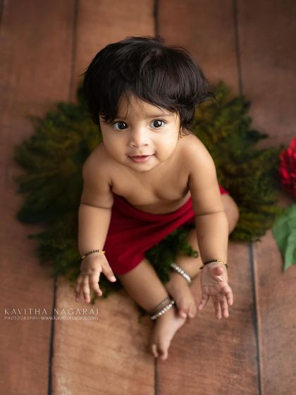 Seven-month-old Monishka looking up with a curious expression. The rich red and green tones create a beautiful, festive feel for this sitter portrait.
