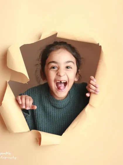 A burst of excitement! The joy on her face as she pops through the paper is absolutely infectious.