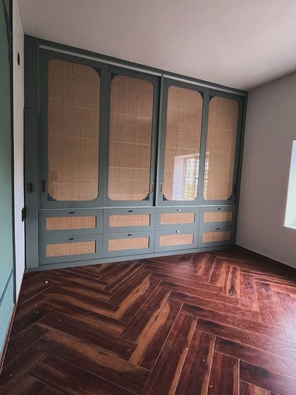 This sliding wardrobe with rattan shutters and a Duco paint finish is a great example of modern-classic design. The herringbone wooden flooring adds another layer of warmth and texture to the room.