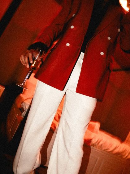 A detail shot focusing on the contrast between the rust blazer and off-white trousers. The white buttons on the jacket tie the entire look together.