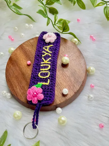Another shot of the custom name tag keychain, resting on a wooden disc. The purple and pink color combination is so pretty.