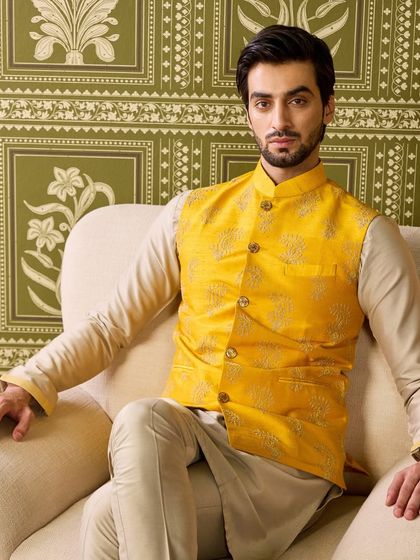 Another take on the perfect Haldi look. This mellow yellow waistcoat features subtle, self-colored embroidery, worn over a beige kurta for a refined and elegant appearance.