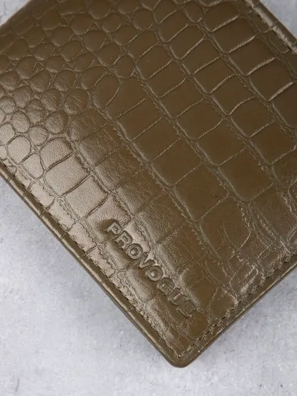 A macro shot of the crocodile texture and embossed logo on the green wallet.