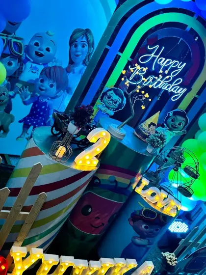 The bright green and blue lights give this Cocomelon setup a playful, cartoonish feel, perfect for a 2-year-old's party.