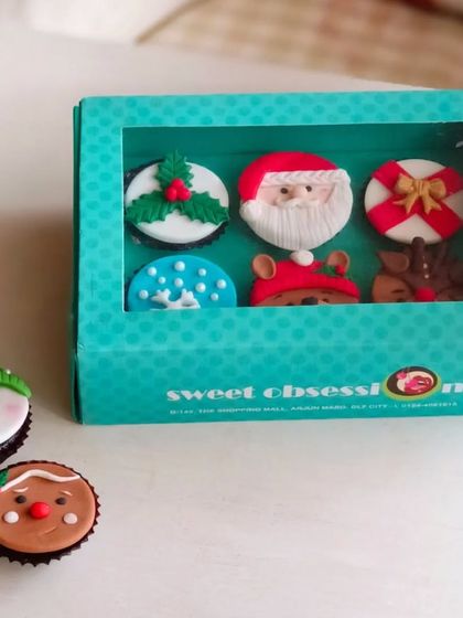 A closer look at my Christmas mini cupcake gift box. This set of six includes assorted festive designs like Santa Claus, a reindeer, a gift box, and mistletoe.