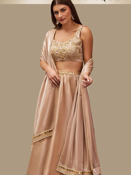 Timeless elegance in champagne gold. This lehenga features a beautifully embroidered blouse and a flowing satin skirt, perfect for a sophisticated evening look at a reception or engagement.