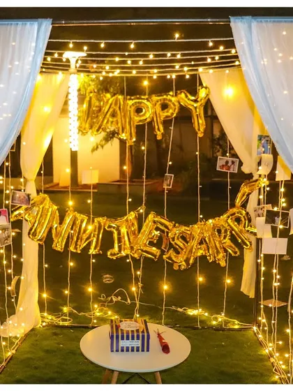 We transform any space into a private romantic getaway with our anniversary cabana decor. This setup includes a canopy of soft white drapes, hundreds of warm fairy lights, and personalized photo displays to celebrate your journey together.