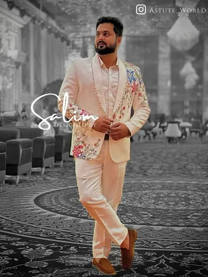 A modern take on formal wear. This is a custom-tailored white suit with asymmetrical floral hand embroidery climbing up one side. It's a distinctive choice for a cocktail party, reception, or any event where you want to stand out.