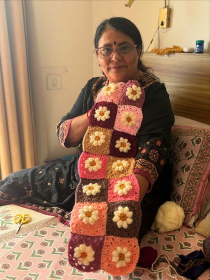 Here I am holding a strip of completed daisy squares before they are joined together. This shows part of the process and the intricate work required for each section of the final custom baby blanket.