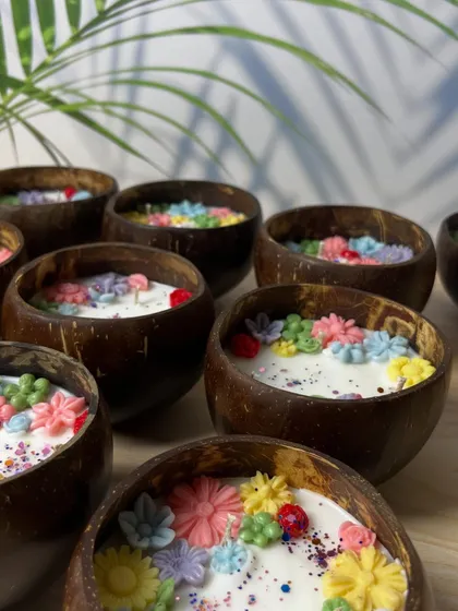 A beautiful shot of our coconut shell candles, filled with colorful wax flowers. This design combines a natural, eco-friendly vessel with a vibrant, playful floral arrangement.