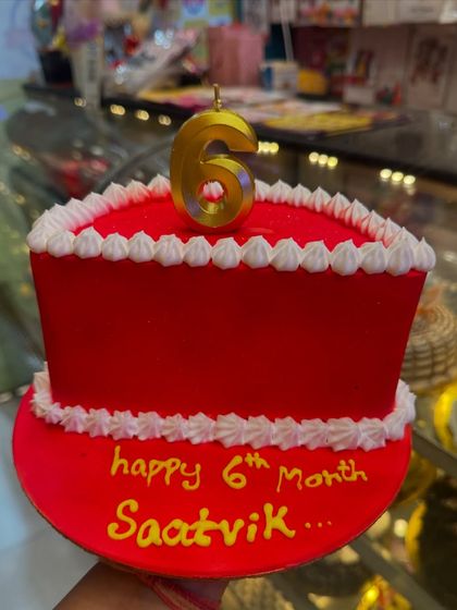 A simple and classic six-month birthday cake. The bold red color and a single number '6' candle make a clear and happy statement for the celebration.