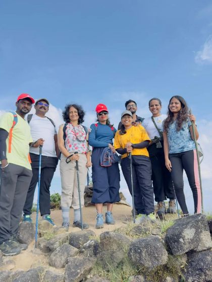 A group photo at the peak, with trekking poles and happy smiles.