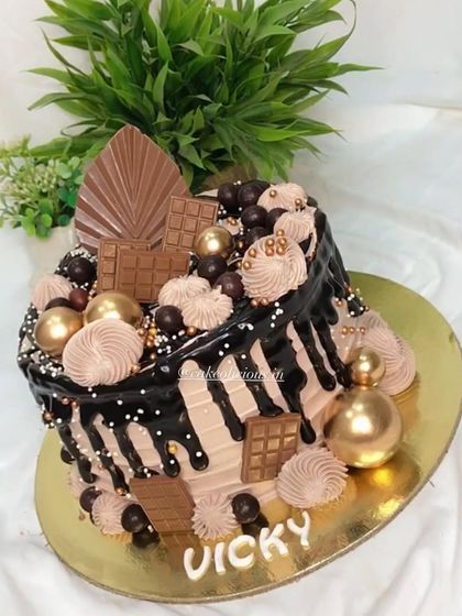 This is not just an ordinary chocolate cake. It's an overloaded drip cake with rich chocolate frosting, chocolate bars, and golden decorative balls.