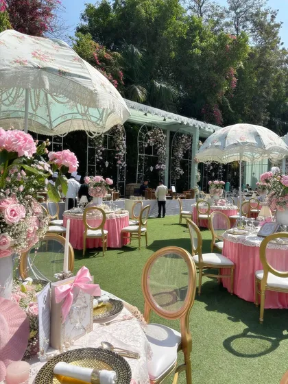 This is a glimpse of a 'Bridgerton' themed luncheon I designed. The outdoor setting features elegant tablescapes with pink floral arrangements, vintage umbrellas, and classic gold-accented chairs to transport guests to a romantic, regency-era garden party.