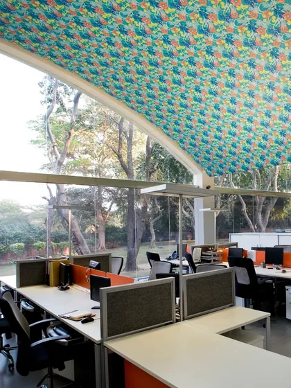 An office workspace with an arched ceiling and a full-height glass wall overlooking a lush green landscape. This is a prime example of our 'Care for Context' philosophy, where we design to maximize the connection between the built environment and nature.