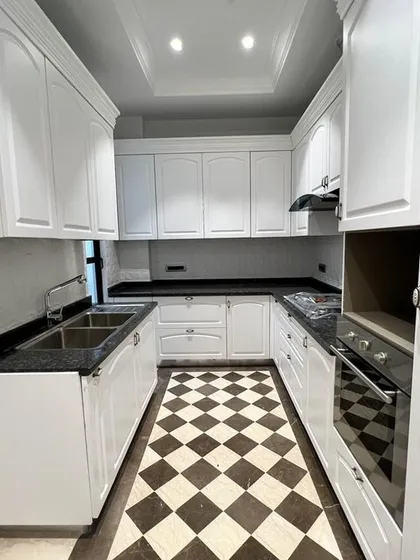 This is our take on a Victorian classical kitchen. It combines timeless design, like the checkerboard flooring and elegant white cabinetry, with modern functionality, including a fully equipped setup with a built-in hob and chimney.