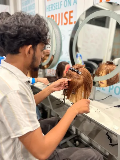 Another student perfecting his hair extension application technique, a skill that requires patience and precision.