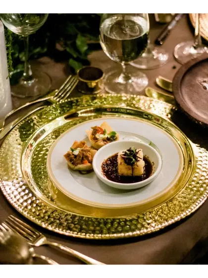 A plated appetizer, featuring silken tofu and flavourful toppings, served on a hammered gold charger plate. This dish exemplifies our approach to creating small plates that are both visually artistic and delicious for a multi course meal.