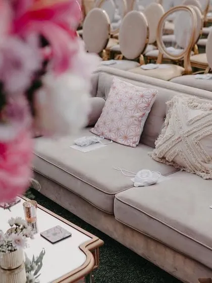 A lounge sofa with custom-printed and textured cushions in shades of pink and cream, providing a comfortable and stylish seating option for guests.