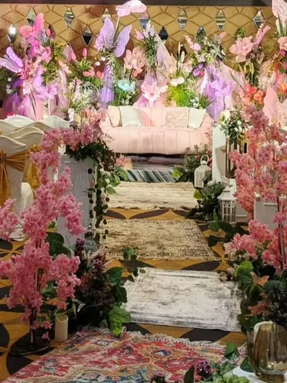 The aisle for this Sangeet was designed to feel like an enchanted forest path, with faux pink cherry blossom trees and Persian rugs leading to the main stage.
