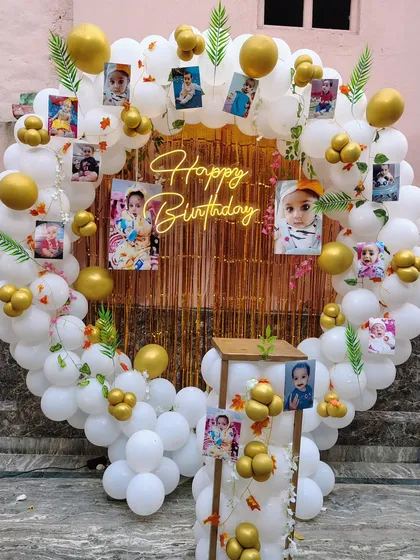 A beautiful birthday backdrop featuring a ring of white and gold balloons, personalized with photos of the birthday baby.