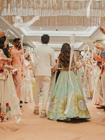 An interactive and joyful entry for the couple at their carnival-themed event, where guests created an archway of white ribbons.