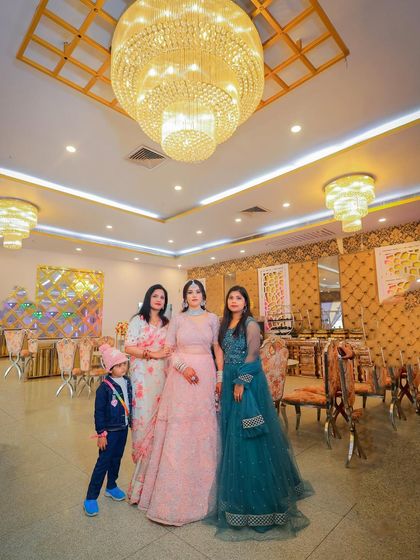 A group photo from a ring ceremony, capturing the couple with their family and friends in the grand venue.