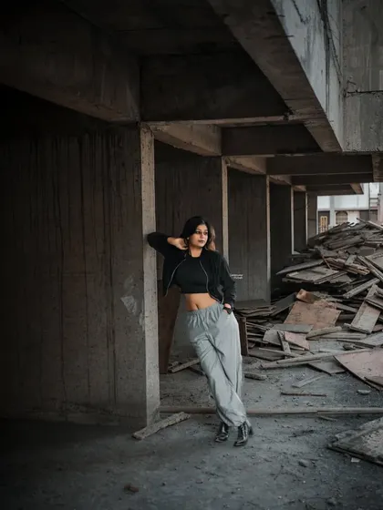 A moody, atmospheric shot inside the construction site, with the model leaning against a concrete pillar, creating a sense of urban solitude.