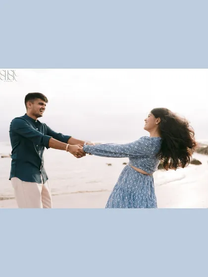 A wide shot of a couple spinning and laughing on the shores of Goa, capturing the full joy of the moment.