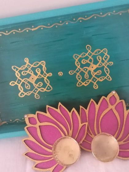 This gift set includes a turquoise Kolam tray and two pink and gold lotus T-light holders. The colors and motifs create a vibrant and festive look, perfect for gifting.
