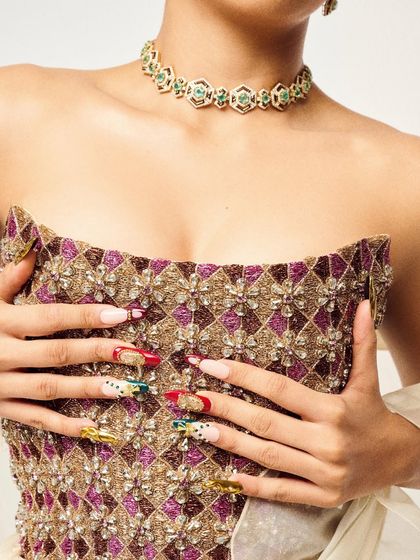 This custom nail set was designed to perfectly match the intricate, traditional embroidery of the outfit. I used a mix of red, green, and gold chrome to create a royal look for this editorial shoot.