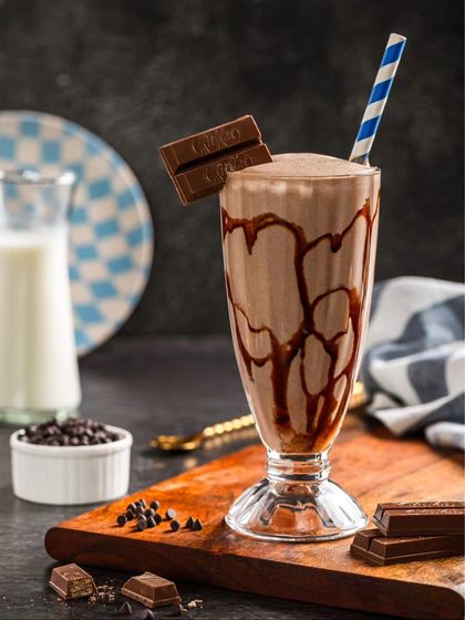 A classic KitKat milkshake, with chocolate syrup drizzled inside the glass and a KitKat bar for garnish.