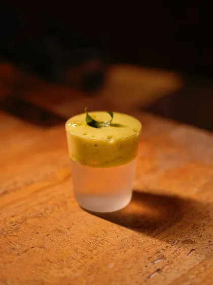 A detailed look at the layered Neer More 2.0, showcasing its vibrant green chili and coriander foam top. It's a drink that's as visually striking as it is flavourful.