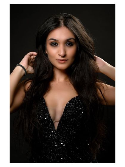 A glamorous studio portrait in a sparkling black dress. The model's pose is elegant and sophisticated.