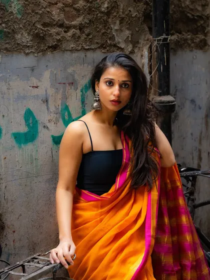 A classic portrait pose that showcases the beautiful saree and the model's expression, framed by the gritty texture of the alley wall.