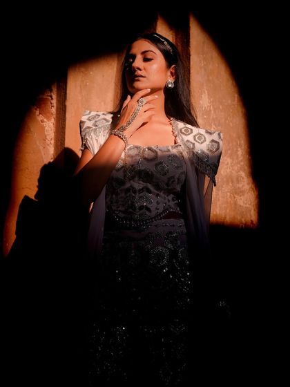 Using shadow and light to create mystery and focus. This image highlights the intricate embroidery of the white pantsuit while shrouding the model in shadow, drawing the viewer's eye to the details.