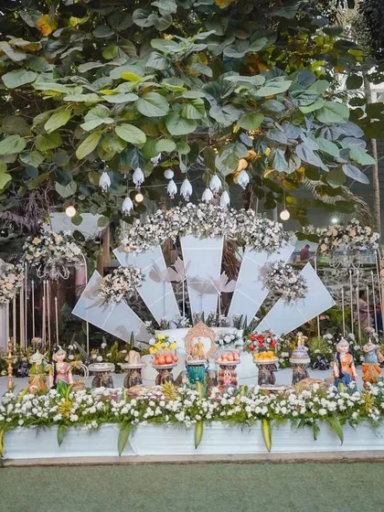 A modern white stage with a fan-like backdrop and white floral arrangements.