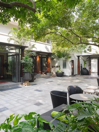 A wide view of the central courtyard, designed as an extension of the indoor living spaces. Shaded by large trees, it is a versatile area used for everything from quiet relaxation to hosting large dinners and classical dance performances.