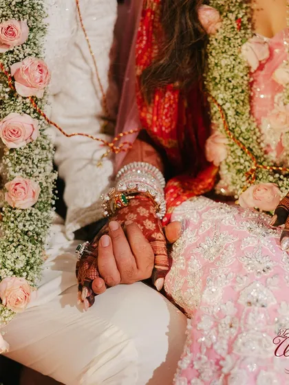 A close-up of the couple's hands during the ceremony, a symbol of their union. The intricate henna, beautiful bangles, and delicate floral garlands all come together.