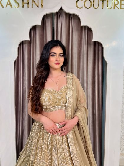 A close-up of a model wearing a sparkly golden lehenga. Her smile says it all. This outfit is designed to make you feel happy and confident.