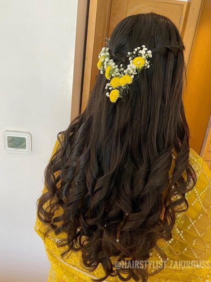 A simple and pretty half-up style with a braided crown and fresh yellow flowers, perfect for a Haldi ceremony.