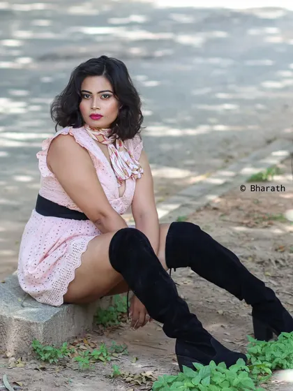 A seated portrait on a concrete ledge, with soft lighting and a natural background.
