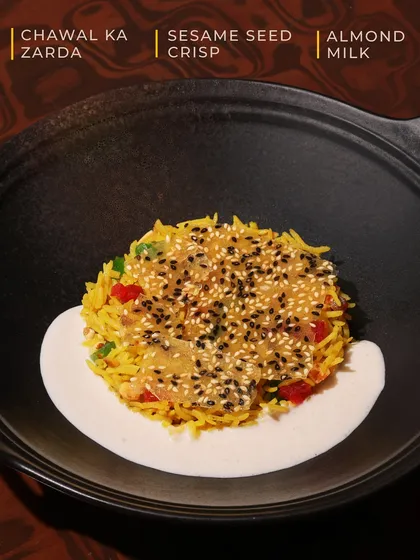 Our Chawal ka Zarda is a dessert that surprises with every bite. Sweet, fragrant rice is layered with a crunchy sesame seed crisp and served over creamy almond milk for a delightful play on textures.