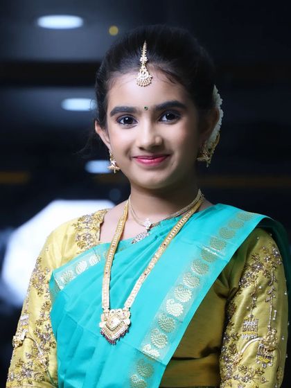 A close-up portrait of Niharika. You can see the soft eye makeup and natural lip color that complements her green and gold outfit.