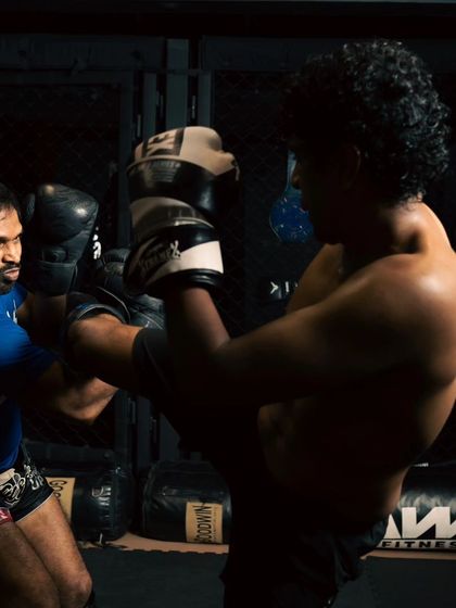 A close-up shot of a high kick being blocked during a sparring session, capturing the intensity and focus in the fighters' eyes.