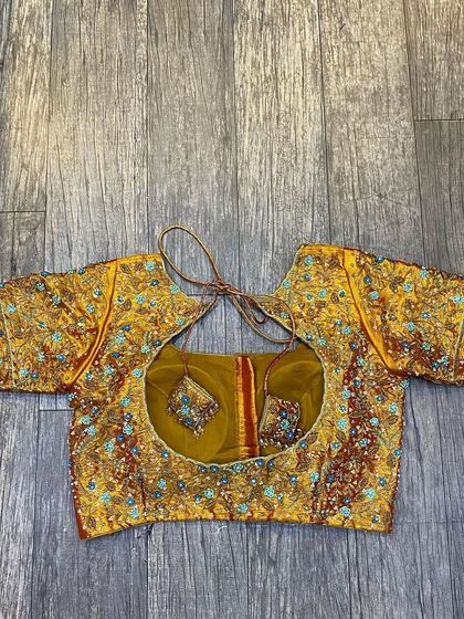 This is a heavily worked blouse with multi-color embroidery. The design is dense and intricate, perfect for pairing with a grand wedding saree.
