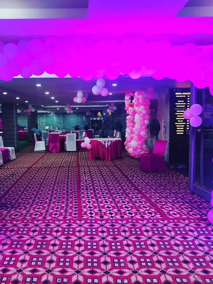 A balloon arch marks the entrance to this birthday party, creating a welcoming gateway for guests as they arrive. The pink lighting adds to the party mood.