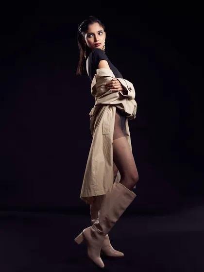 The addition of a trench coat adds a layer of mystery and sophistication. The hair and makeup remain the focal point, creating a look that is both classic and modern.