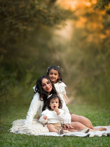 A quiet moment with mom and her two girls. The soft, dreamy background of the park adds to the tenderness of this beautiful mother-daughter portrait.